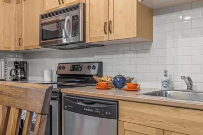a kitchen with a stove microwave and a sink at Chic 1BR City Nest Heated Parking and Hot Tub and Pool in Canmore