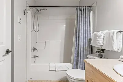 a white bathroom with a shower and a toilet at Chic 1BR City Nest Heated Parking and Hot Tub and Pool in Canmore