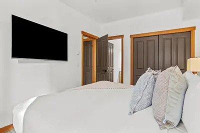 a bedroom with a white bed with a flat screen tv at 3BR Family Friendly Getaway Pool and Hot Tub in Canmore