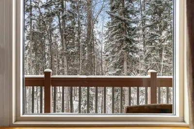 a window with a view of a snow covered forest at 3BR Family Friendly Getaway Pool and Hot Tub in Canmore