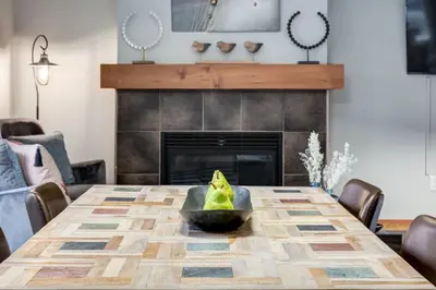 a dining room with a table and a fireplace at Lovely 2BR Canmore Condo w Heated Pool and Hot Tub in Canmore