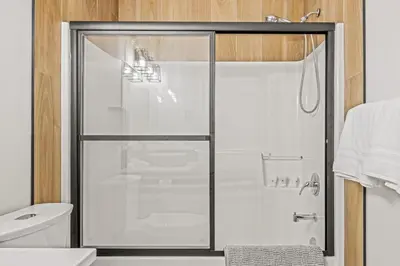 a shower with a glass door in a bathroom at Spacious 2BR Minutes from Downtown w Pool and Hot Tub in Canmore