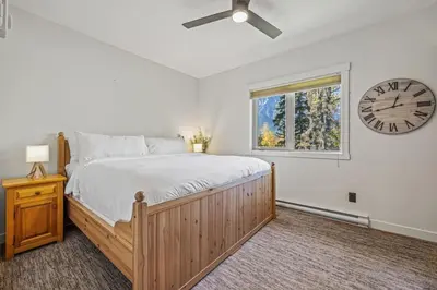a bedroom with a large bed and a clock on the wall at Spacious 2BR Minutes from Downtown w Pool and Hot Tub in Canmore