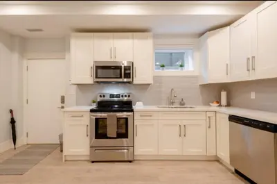 a kitchen with white cabinets and a stove and microwave at 2BR Suite Close to Transit - Great for FIFA Vancouver in Burnaby