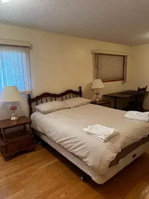 a bedroom with a large bed with two tables and two lamps at Cozy Farmhouse B&B Retreat in Williams Lake