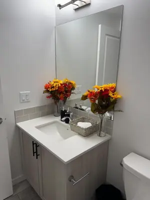 a bathroom with a sink with a mirror and flowers at Luxury Haven by Kc & Flo in Calgary