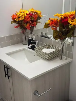 a bathroom sink with flowers in vases on it at Luxury Haven by Kc & Flo in Calgary