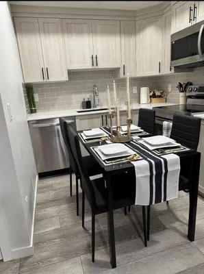 a kitchen with a dining room table with black chairs at Luxury Haven by Kc & Flo in Calgary