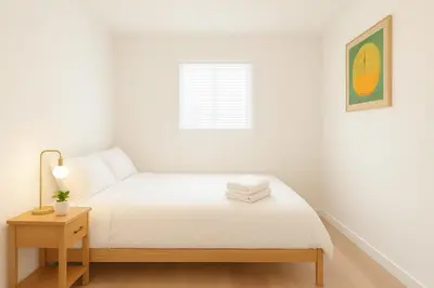a white bedroom with a bed and a window at Sweet 2-bedrooms house in Vancouver in Vancouver