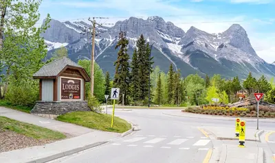 an empty road with a sign and mountains in the background at Sleeps 8 Loft with Pool Hot Tub Near Banff in Canmore