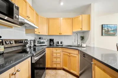a kitchen with wooden cabinets and stainless steel appliances at Sleeps 8 Loft with Pool Hot Tub Near Banff in Canmore