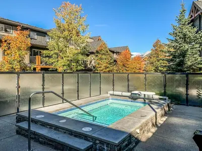 a hot tub in a backyard with a fence at Rockies Getaway 2BR with Patio Hot Tub and Gym in Dead Man's Flats
