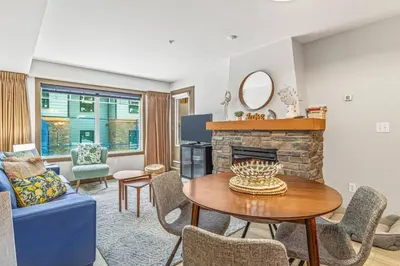 a living room with a table and a fireplace at Contemporary 2BR with hot tub and Mountain Views in Dead Man's Flats