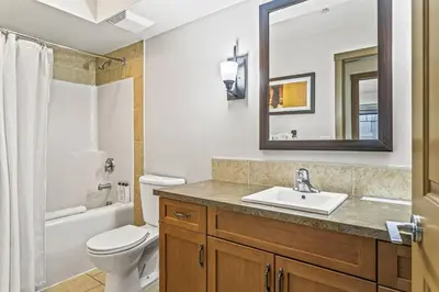 a bathroom with a sink and a toilet and a mirror at Contemporary 2BR with hot tub and Mountain Views in Dead Man's Flats