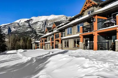 a snow covered street in front of a mountain at Cozy Condo With Hot Tub Gym and Underground Parking in Dead Man's Flats