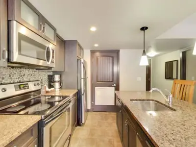 a kitchen with stainless steel appliances and granite counter tops at Cozy Condo With Hot Tub Gym and Underground Parking in Dead Man's Flats