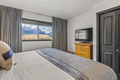 a bedroom with a bed and a tv and a window at Amazing 3BR Condo With Hot Tub Access and Mtn Views in Dead Man's Flats