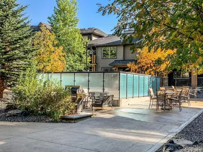 a patio with chairs and tables in front of a house at Amazing 3BR Condo With Hot Tub Access and Mtn Views in Dead Man's Flats