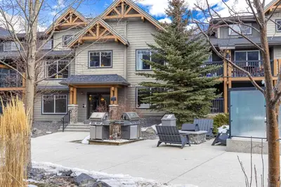 a house with a fire grill in front of it at Lovely 3BR condo with Hot Tub at the Edge of Canmore in Dead Man's Flats
