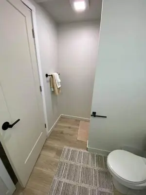 a bathroom with a toilet and a door with a rug at New! Spacious Bright Home in GREAT Location in Red Deer