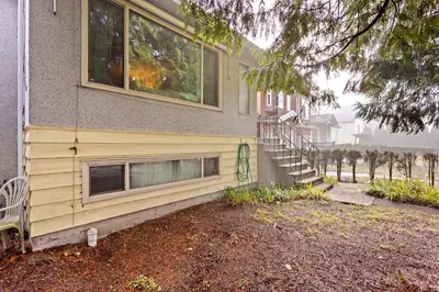 a house with a yellow siding and a stair case at Newly Renovated Cozy Guest House In Joyce-Collingwood in Vancouver