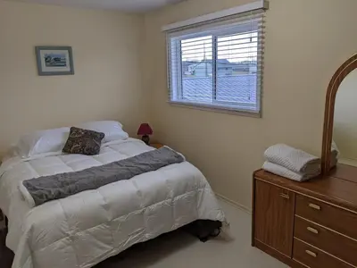 a bedroom with a bed and a dresser and a window at Dragon's End Guesthouse in Massett