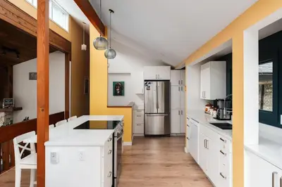 a kitchen with white cabinets and a refrigerator at The Mushroom Manor B&B and Cedar Sauna in Salt Spring Island