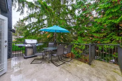 a patio with a table and a grill and an umbrella at Cozy 3BR Family Home near City Centre & SkyTrain in Coquitlam