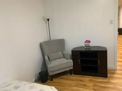 a bedroom with a chair and a dresser and a lamp at ArtHaus Downtown Emma Barr Unit 3BR 1BA in Whitehorse