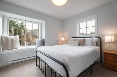 a white bedroom with a bed and two windows at Englewood Greens 40 by Outpost Whistler in Whistler