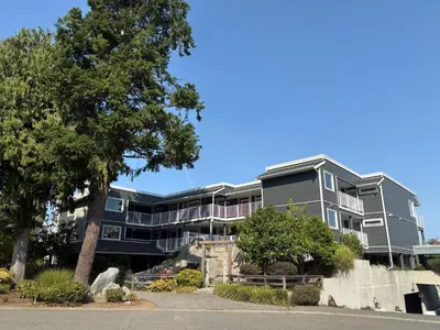 an apartment building with a tree in front of it at Oceanside Getaway in Nanoose Bay