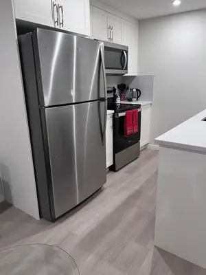 a stainless steel refrigerator in a kitchen with white cabinets at The Lakefront - A new 2-bedroom in Mahogany Calgary in Calgary