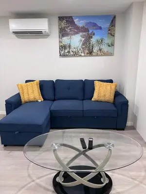 a living room with a blue couch and a glass table at The Lakefront - A new 2-bedroom in Mahogany Calgary in Calgary