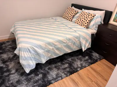 a bed with a striped comforter in a bedroom at Home away from Home in Edmonton