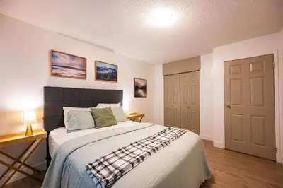 a bedroom with a bed and a table and a door at Bearberry Premium Rentals in Whitehorse