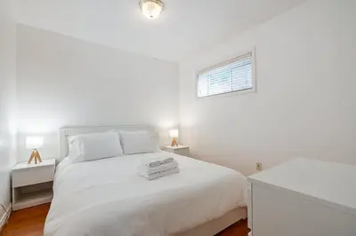 a white bedroom with a white bed and a window at Private Guest Suite with Kitchen in Vancouver