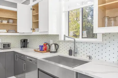 a white kitchen with a sink and a window at 8BR New Spacious Home White Rock HVAC Free Parking in Surrey