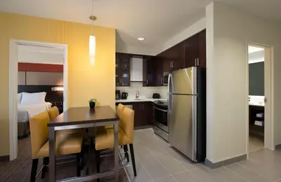 a kitchen and dining room with a table and a refrigerator at Residence Inn by Marriott Calgary South in Calgary
