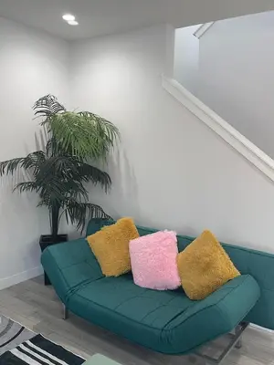 a green couch with colorful pillows on it in a room at Exquisite 4BR & 3 Baths 2000sqft Home in Calgary