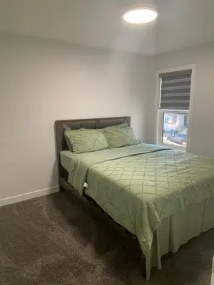 a bedroom with a bed with a green comforter and a window at Exquisite 4BR & 3 Baths 2000sqft Home in Calgary