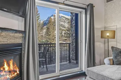 a living room with a fireplace and a view of a mountain at Amazing Views 1BR Condo with Hot Tub and Pool in Canmore