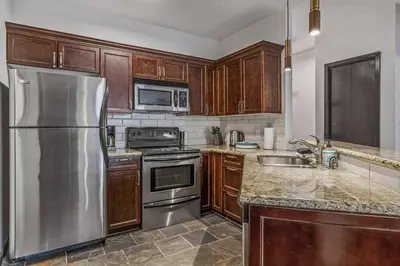 a kitchen with wooden cabinets and a stainless steel refrigerator at Amazing Views 1BR Condo with Hot Tub and Pool in Canmore