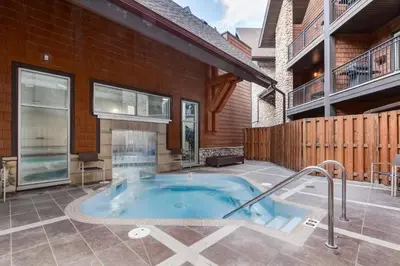 a hot tub in a yard next to a building at Amazing Views 1BR Condo with Hot Tub and Pool in Canmore