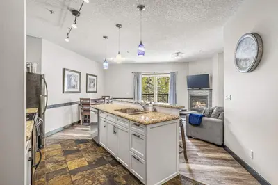 a kitchen with a sink and a living room at 2BR Scenic Rockies Retreat BBQ Hot Tub and Pool in Canmore