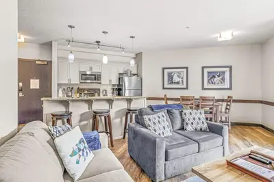 a living room with a couch and a kitchen at 2BR Scenic Rockies Retreat BBQ Hot Tub and Pool in Canmore