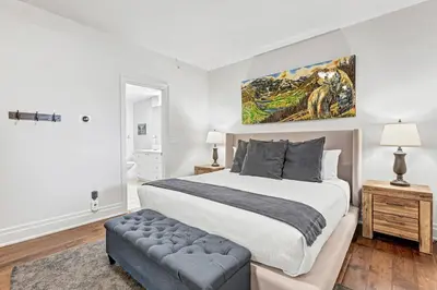 a bedroom with a bed and a painting on the wall at LUXUS 4BR Penthouse 2500sqft with Private Hot Tub in Canmore