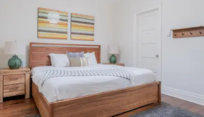 a bedroom with a wooden bed with white sheets at LUXUS 4BR Penthouse 2500sqft with Private Hot Tub in Canmore