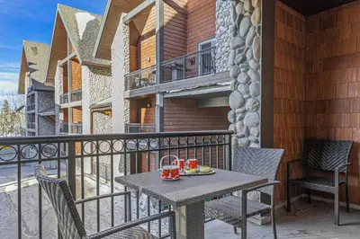 a patio with a table and chairs on a balcony at Perfect Rockies Escape with Pool, Hot Tub and Gym in Canmore