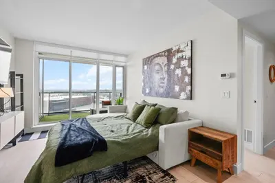 a bedroom with a bed and a large window at Downtown Calgary Modern 1BR with Pullout couch in Calgary
