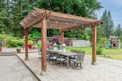 a wooden pergola with a table and chairs at The Wood Shed with hot tub in Oyster Bay